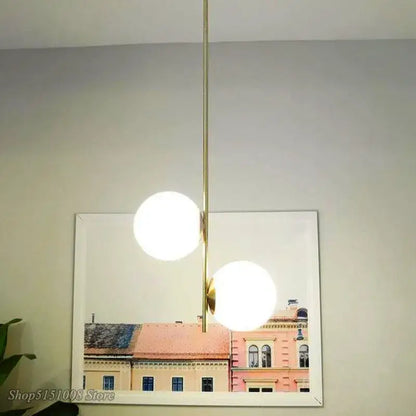 Modern gold glass ball led pendant light with two glowing white spherical bulbs suspended on a slender rod decorbites pendant light