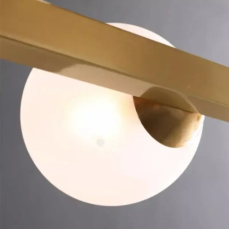 Modern gold glass ball led pendant lights featuring a warm glowing glass ball led shade with brass decorbites bar