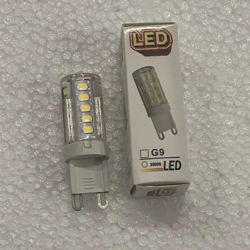 Clear glass ball led bulb with yellowish leds and gray g9 base next to packaging for decorbites glass ball pendant lights