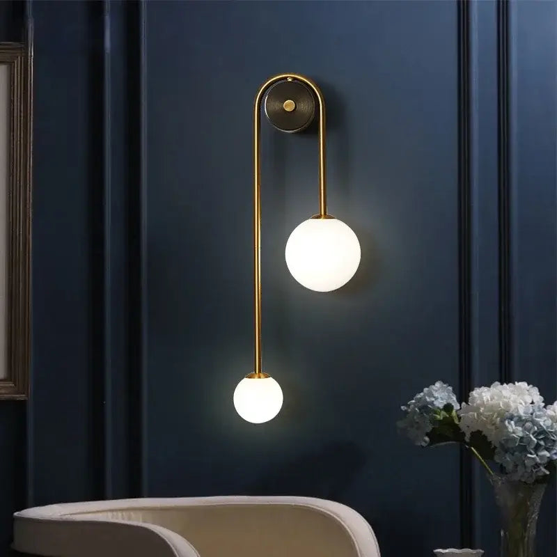 Modern gold wall lamp with two frosted glass ball led shades on a curved metal arm for bedroom and study decorbites glass ball