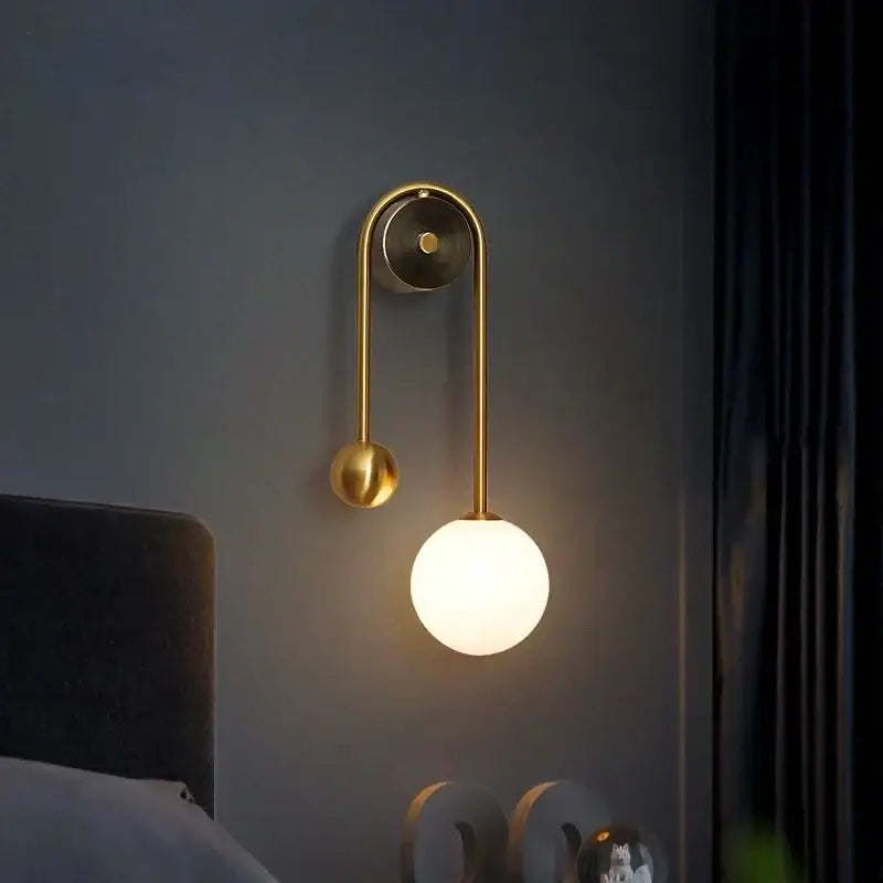 Modern gold wall lamp with curved arm and glass ball led shade ideal for bedroom and study decorbites glass ball design