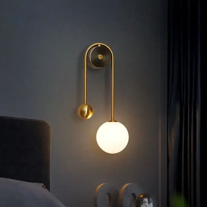 Modern gold wall lamp with curved arm and glass ball led shade ideal for bedroom and study decorbites glass ball design