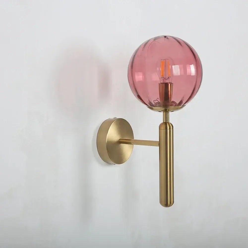 A sleek brass wall lamp with a pink decorbites glass ball led globe for modern bedroom lighting decor