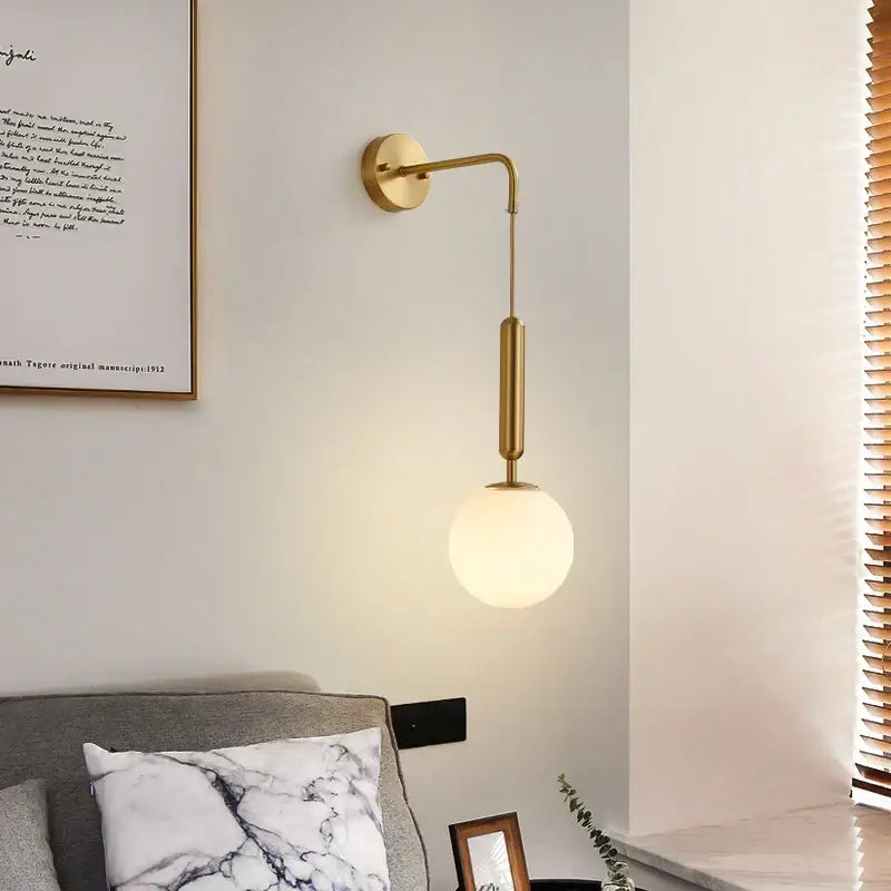 Modern gold wall sconce with a sleek curved arm and frosted glass ball led shade for decorbites bedroom decor