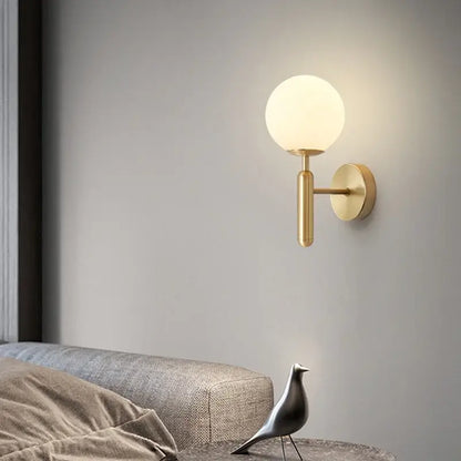 Modern gold glass ball mirror wall lights featuring a gold-toned wall sconce with frosted glass globe shade by decorbites