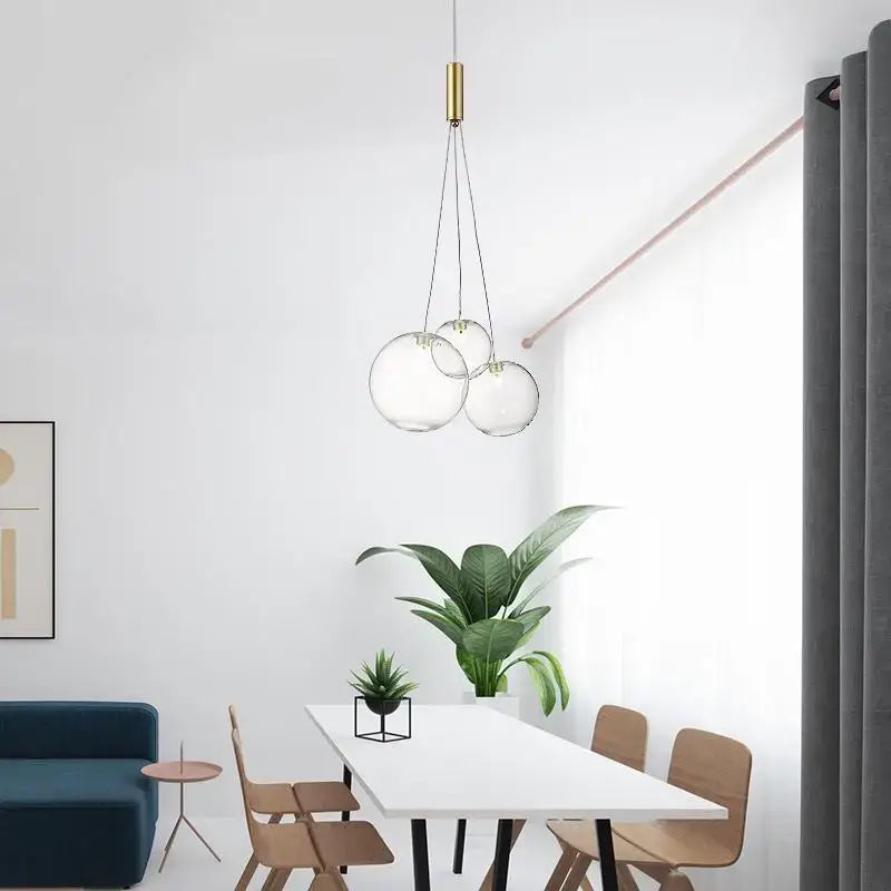 Modern gold glass ball pendant chandelier featuring three clear glass spheres and a gold-toned pendant light fixture