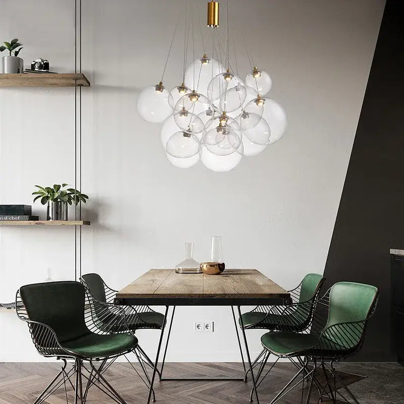 Modern gold pendant chandelier with glass ball globes and brass accents hanging above wooden dining table
