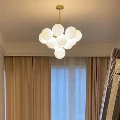 Modern gold glass ball pendant chandelier featuring white glass globe and gold-toned metal frame for dining room decorbites glass ball