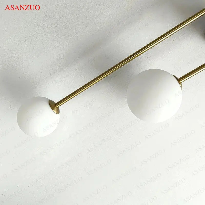 Modern gold glass ball wall lamp with dual frosted matte white glass ball shades on slender gold rods by decorbites