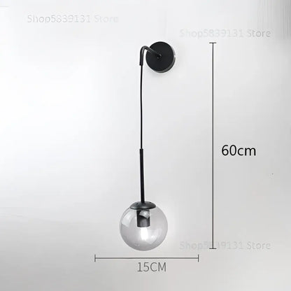 A sleek black wall lamp with a transparent glass ball and slender metal stem for modern bedroom decorbites glass ball