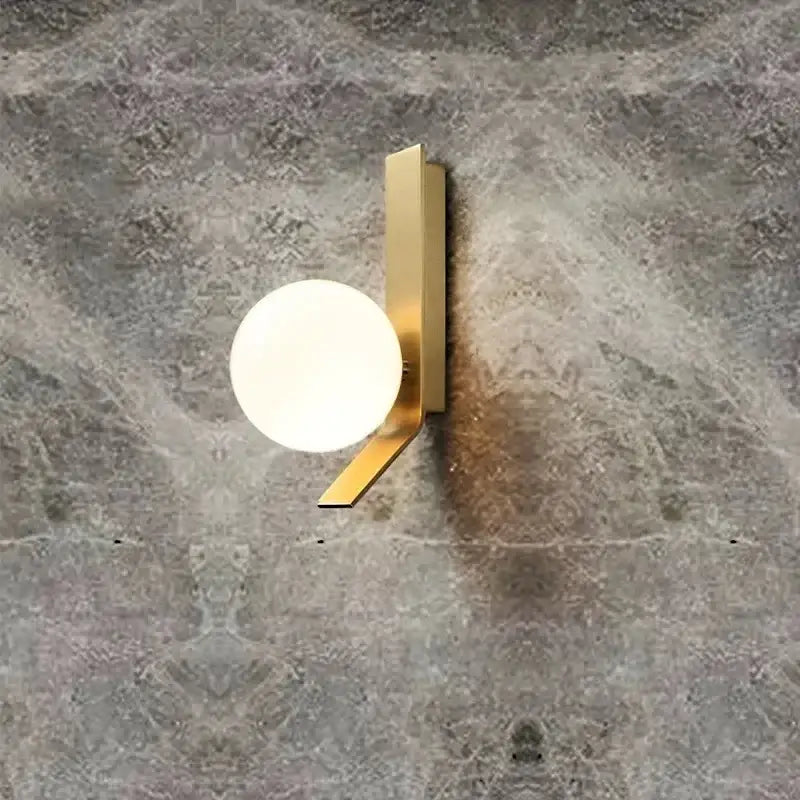 Modern gold wall sconce with a sleek angular metal frame and frosted glass ball diffuser for minimalist decorbites glass ball decor