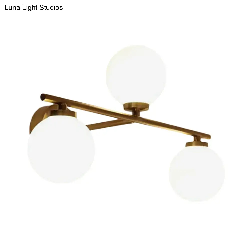 Modern wall lamp featuring a brass-finished ceiling light fixture with three frosted globe opal glass shades