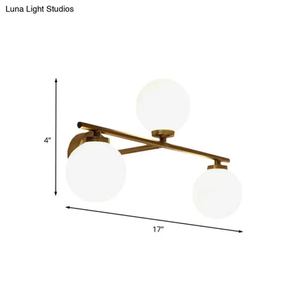 Modern wall lamp with brass finish and three frosted globe opal glass shades for bedroom sconce lighting