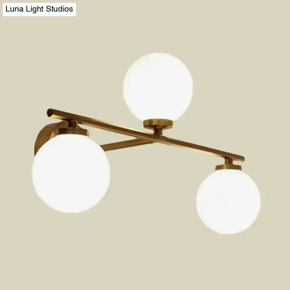 Modern wall lamp with brass finish and three white globe opal glass globes for elegant bedroom lighting