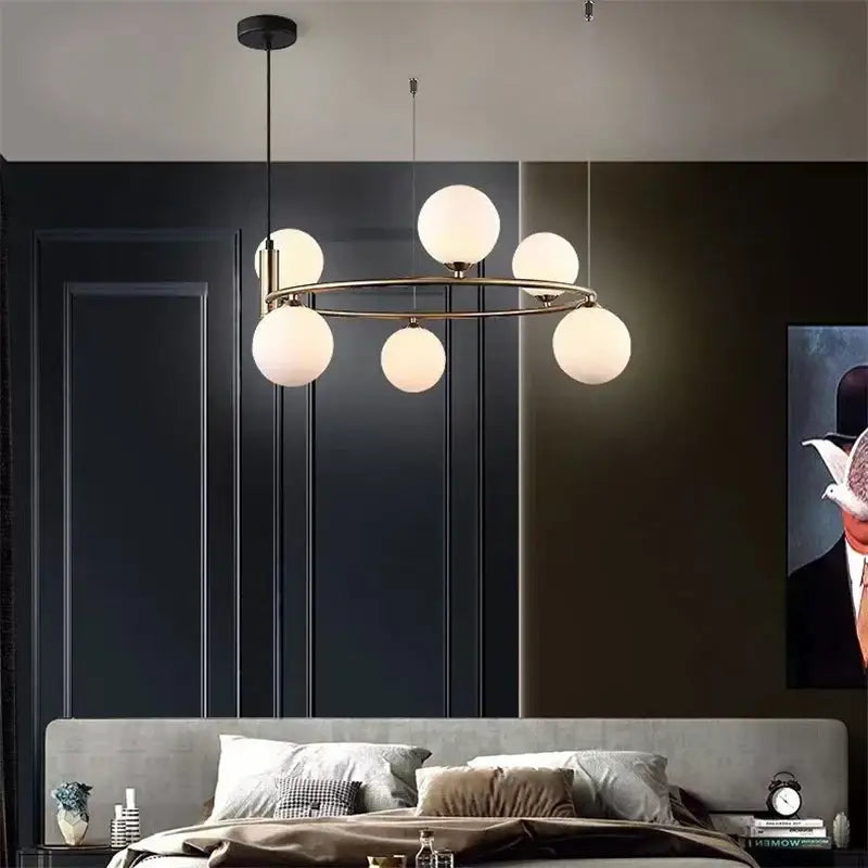 Modern gold brass-toned pendant light chandelier with six frosted glass globes for adjustable dining room lighting