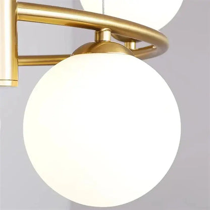 Gold-toned metal frame pendant light chandelier with frosted white glass globe for modern dining room lighting