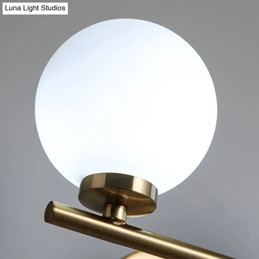 A sleek modern gold globe shade wall sconce with brass finish and frosted opal glass for washroom lighting