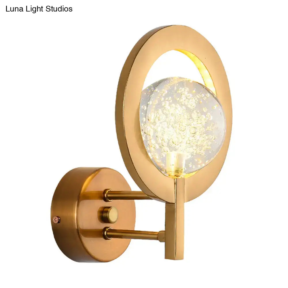 Modern gold globe wall lamp with a gold-toned circular frame and illuminated glass globe with bubbles 110v-120v