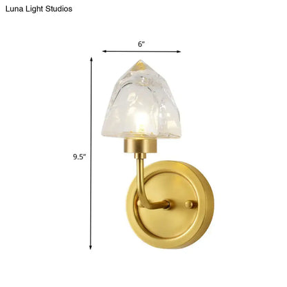 Gold finished wall light with faceted clear glass shade featuring a modern gold ice cube design for bedroom use