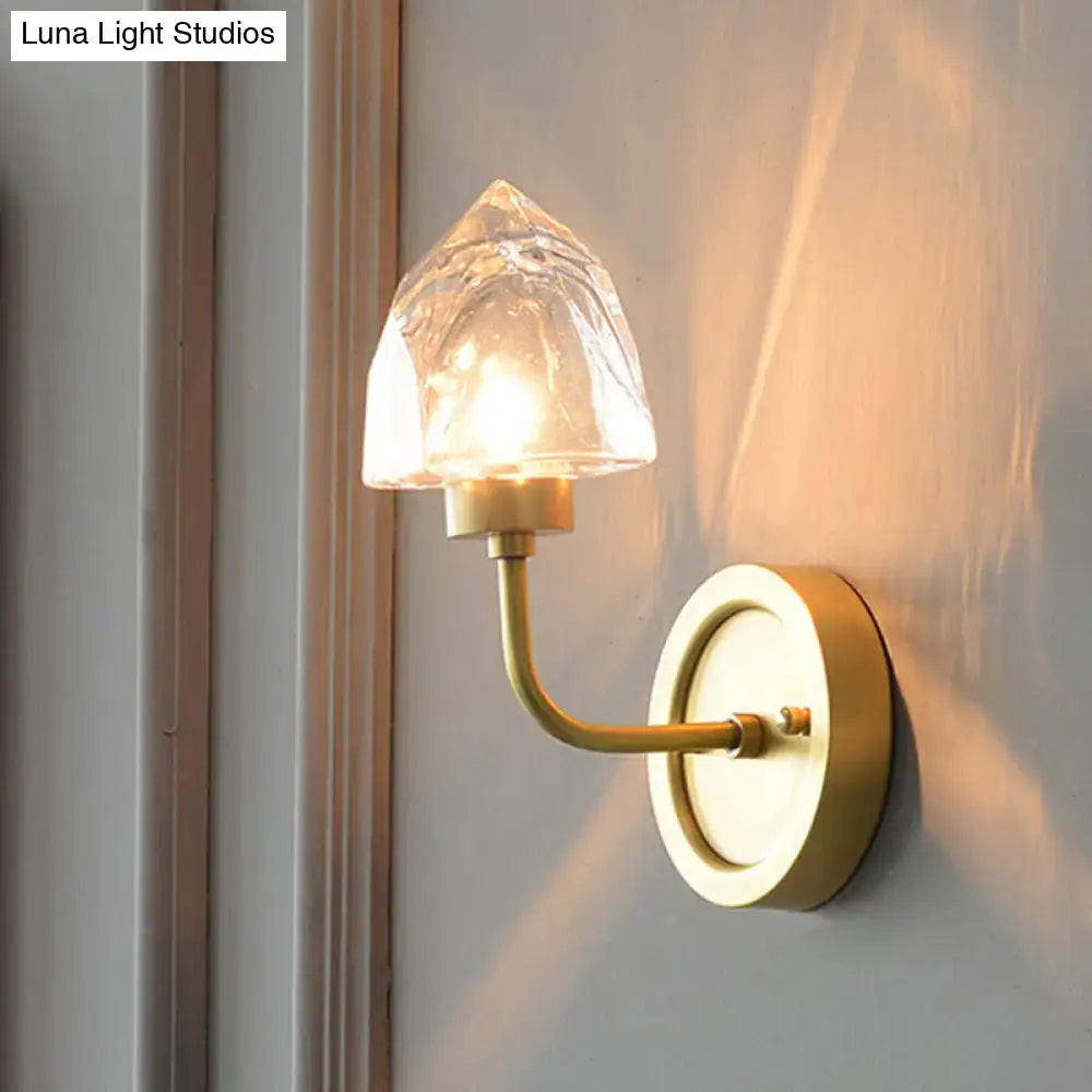 A warm-toned brass wall light with a textured translucent glass shade shaped like a gold ice cube crystal sconce