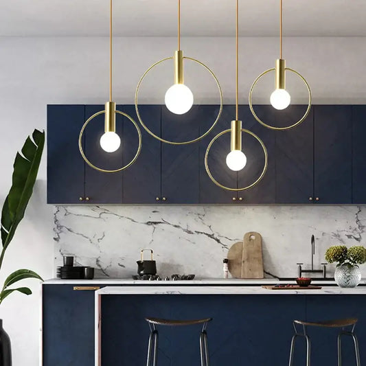 Modern gold ins wind single pendant light with circular gold-toned fixture and exposed bulb hanging above kitchen island
