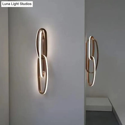 Modern copper-toned wall lamp with intertwined circular design and glowing led light strip for living room use