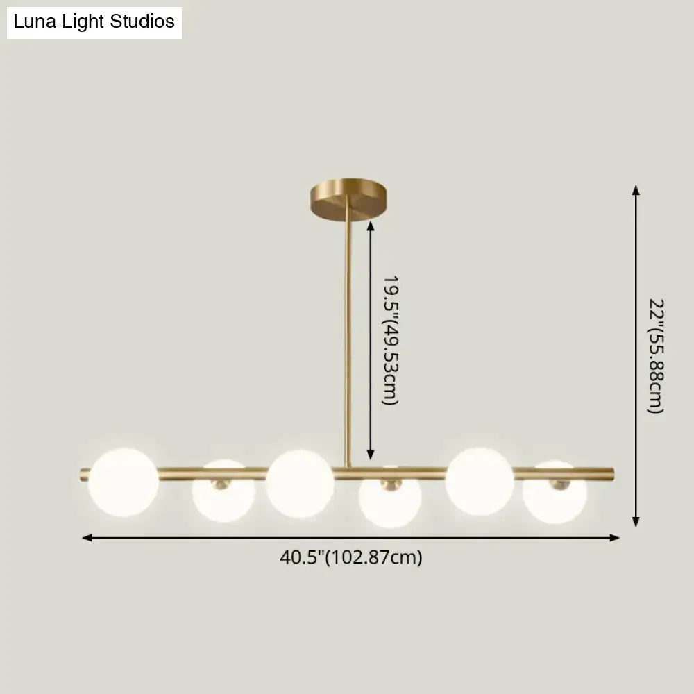 Modern gold island pendant lighting featuring brass finish and five frosted glass globe shades for dining room pendant lighting