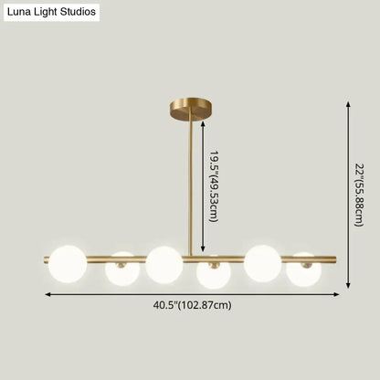 Modern gold island pendant lighting featuring brass finish and five frosted glass globe shades for dining room pendant lighting
