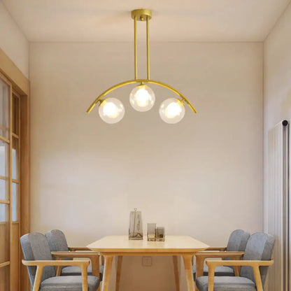 Gold-toned decorbites island pendant with clear white shade and three spherical glass bulbs for modern kitchens