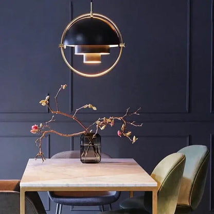 Modern gold layered danish pendant light featuring a black and gold spherical pendant light above a dining table