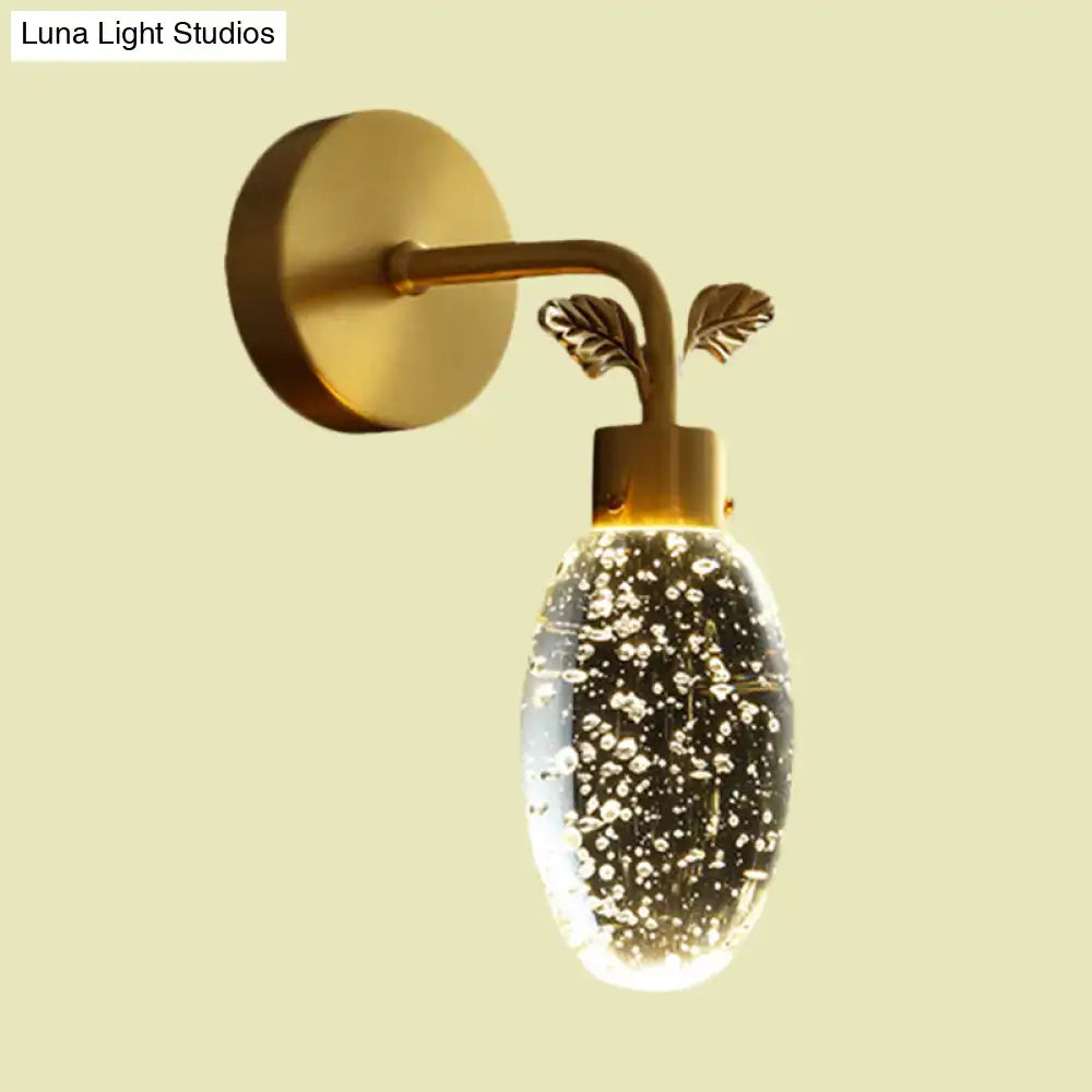 Modern gold led wall sconce with seeded crystal globe filled with bubbles and gold leaf metal accents for bedroom use