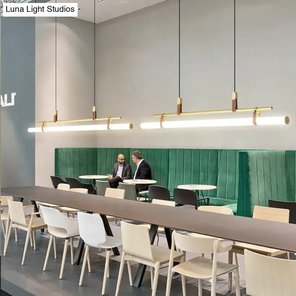 Modern gold led pendant light with wooden accents and leather details hanging in a dining room setting