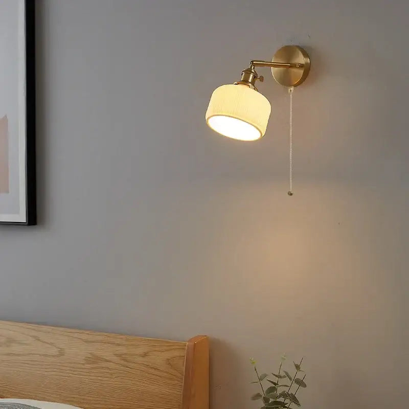 Brass-finished modern gold led wall light with cream ribbed fabric shade and adjustable arm for bedroom reading