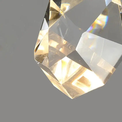 Modern gold led wall sconce with a faceted transparent crystal pendant reflecting light for living room use