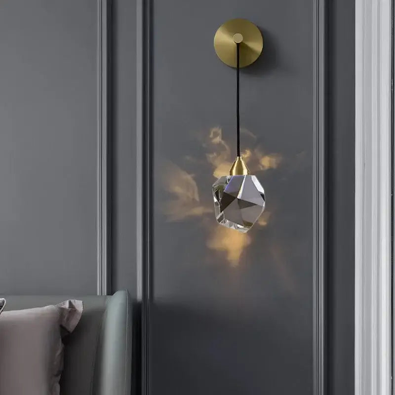 Modern gold led wall sconce with crystal pendant featuring irregular clear glass shade and black cord for living room lighting
