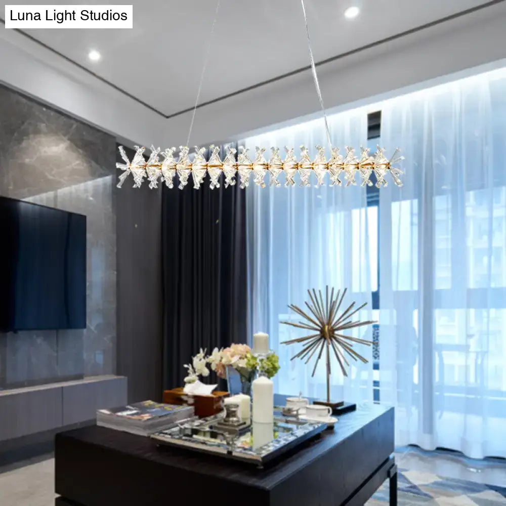 Modern gold linear crystal island lamp with crystal starburst accents hanging above living room table fixture width visible