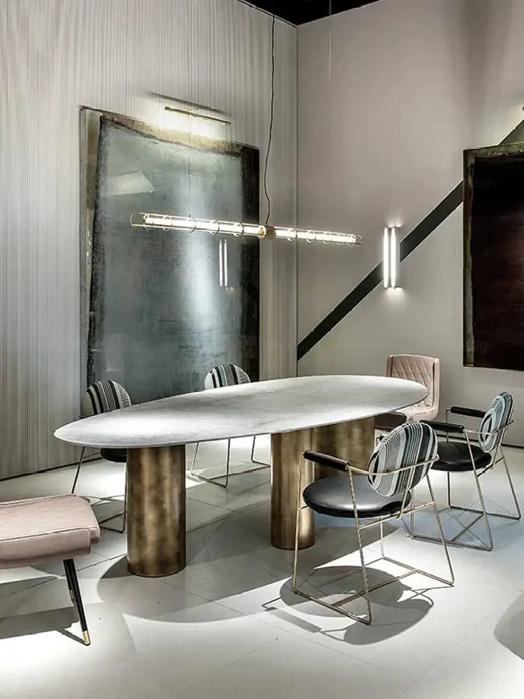 Modern gold linear glass dining room chandelier above an oval marble dining table with bronze cylindrical legs decorbites glass dining