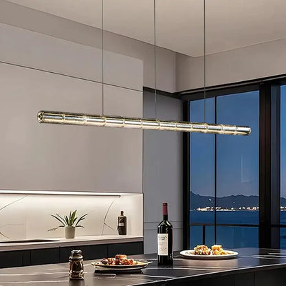 Modern gold linear glass led chandelier with segmented cylindrical design hanging above kitchen island lighting