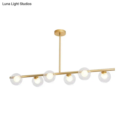 Modern gold linear island light fixture with five clear glass globe shades and sleek horizontal bar design