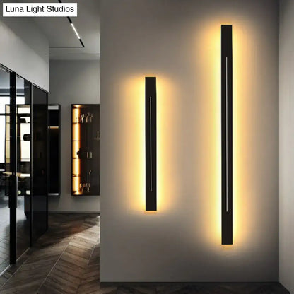 Two sleek black rectangular wall light fixtures with warm yellow backlighting for modern living room decor