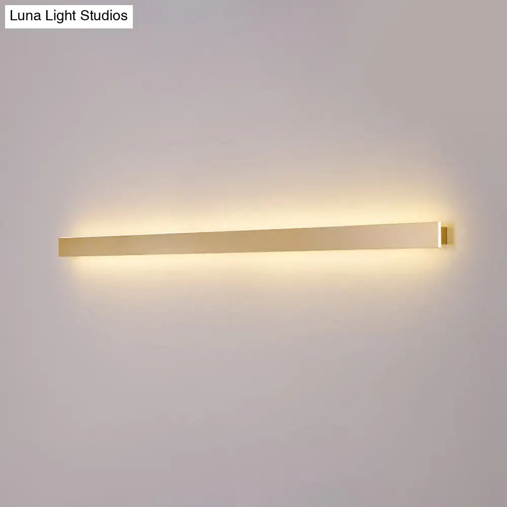 Modern gold linear wall light fixture with a sleek rectangular design emitting warm ambient stairway illumination