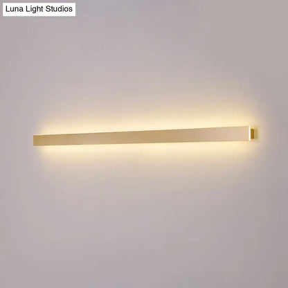 Modern gold linear wall light fixture with a sleek rectangular design emitting warm ambient stairway illumination