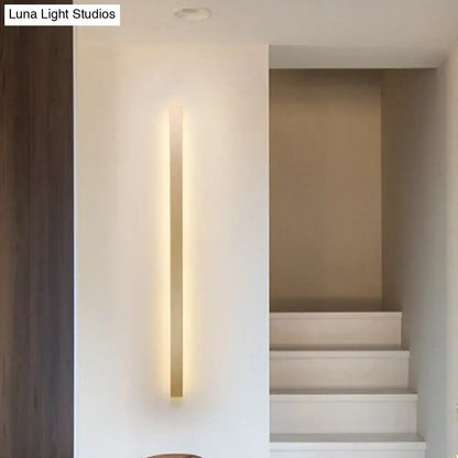 Modern gold linear wall light fixture with a slim vertical design and warm golden glow for stairway ambient lighting