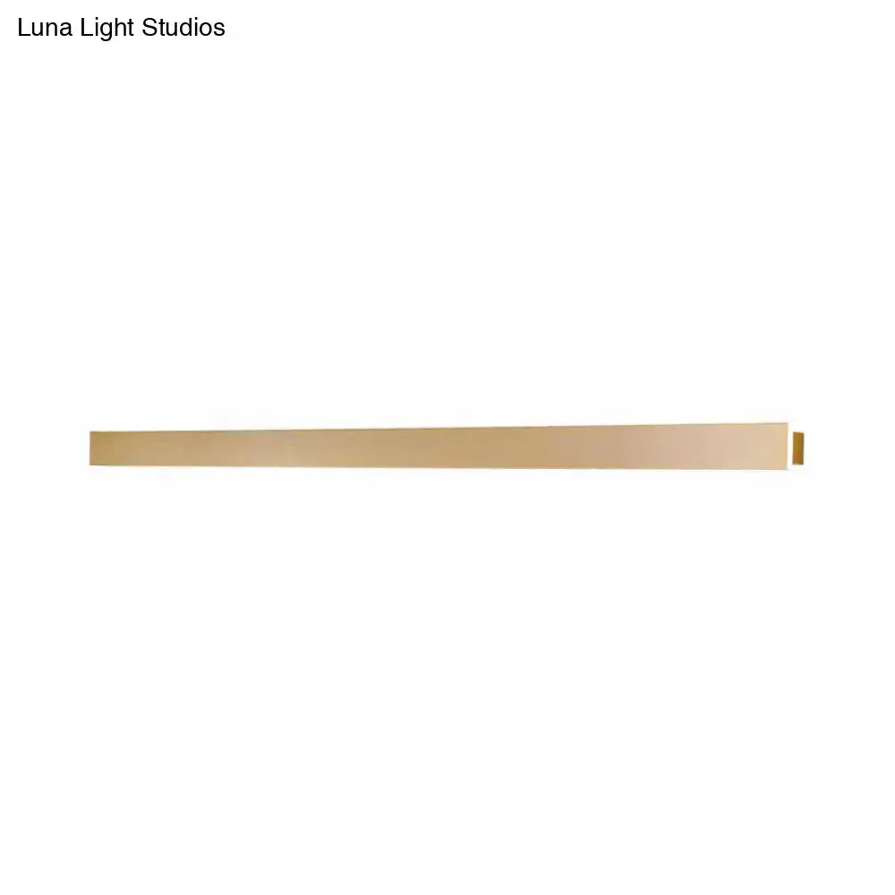 A sleek minimalist brass wall light fixture with a long rectangular design for stairway ambient lighting