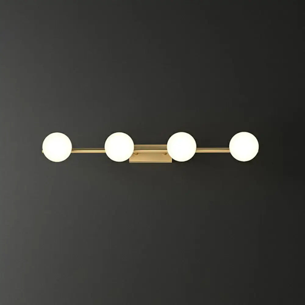 Modern gold linear wall sconce with four evenly spaced milky ball glass globe bulbs for bathroom lighting