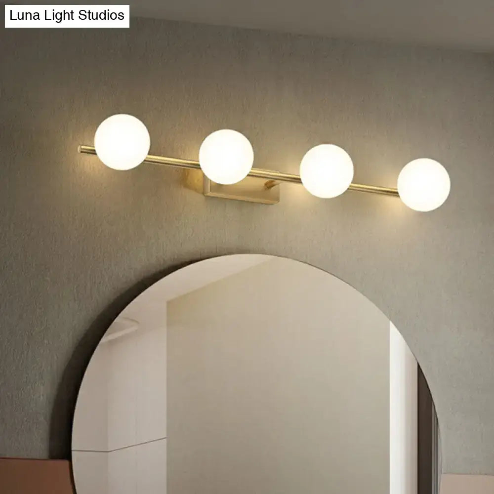 Modern gold linear wall sconce with four spherical milky ball glass bulbs on a sleek brass bar for bathroom use