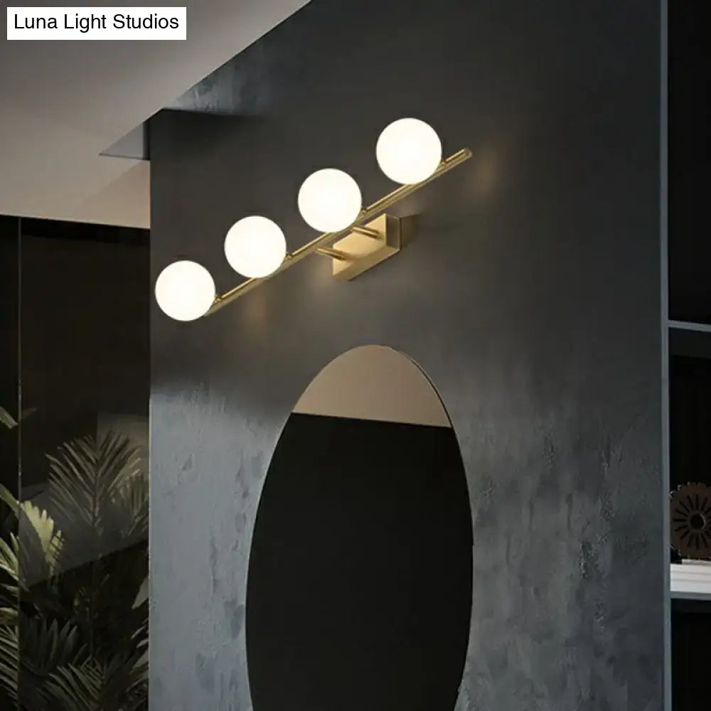 Modern gold linear wall sconce with four milky ball glass bulbs arranged diagonally for bathroom lighting