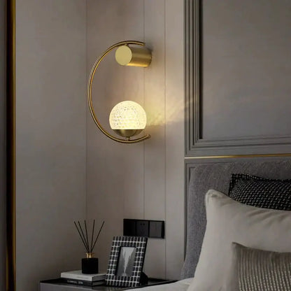 Modern gold luxury creative led bedside wall lamp featuring a gold-toned crescent sconce with textured frosted glass globe