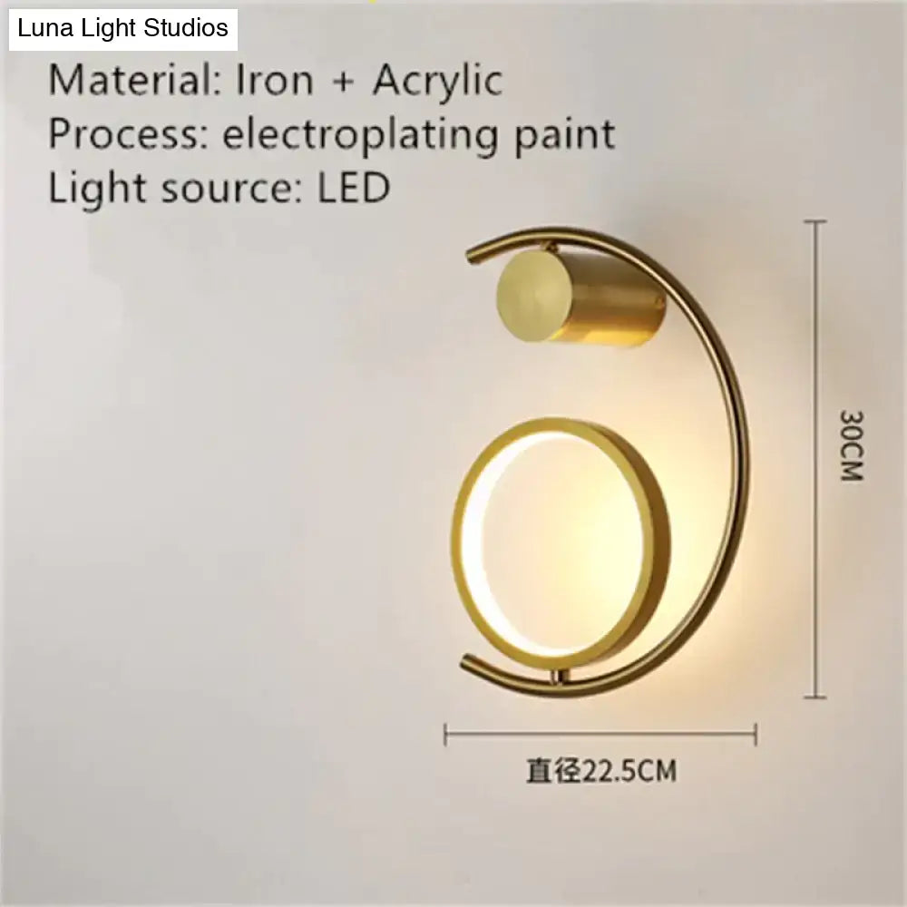 Gold-toned crescent-shaped luxury creative led bedside wall sconce with circular acrylic diffuser and iron frame