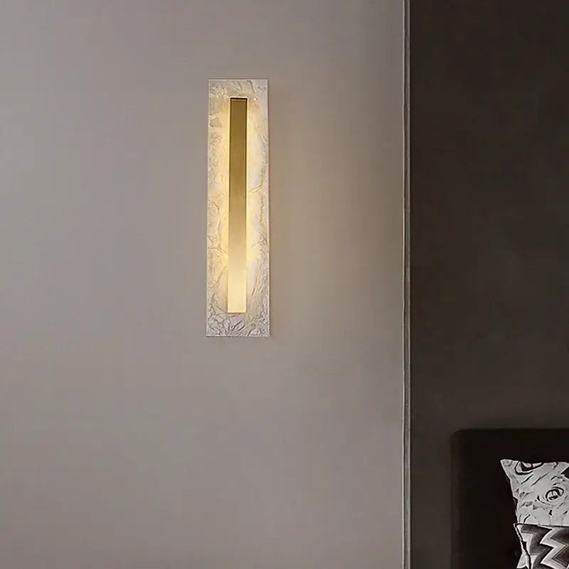 Modern gold marble living wall lamp with frosted glass and warm glowing brass bar in a white marble frame decorbites gold marble